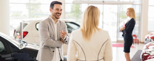 Customer looking at cars at dealership and talking to salesperson